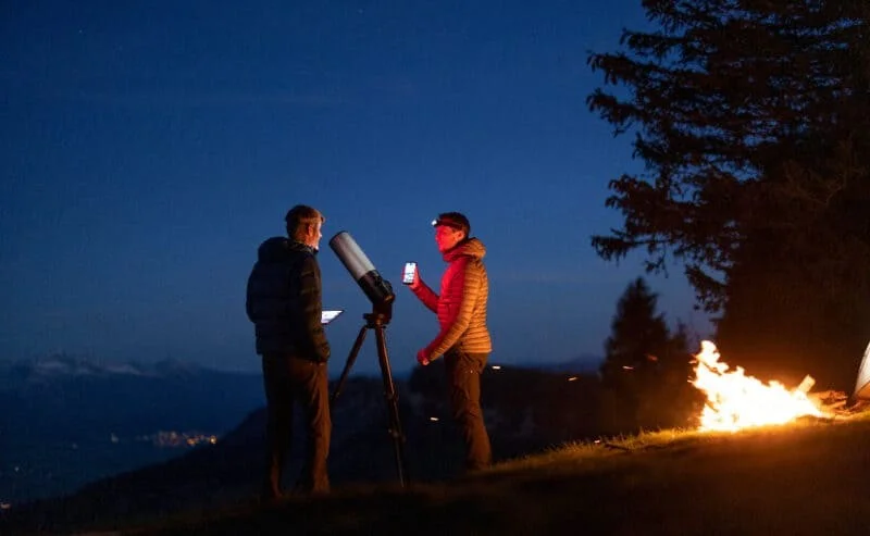 Two astronomers using a smart telescope under the stars at twilight